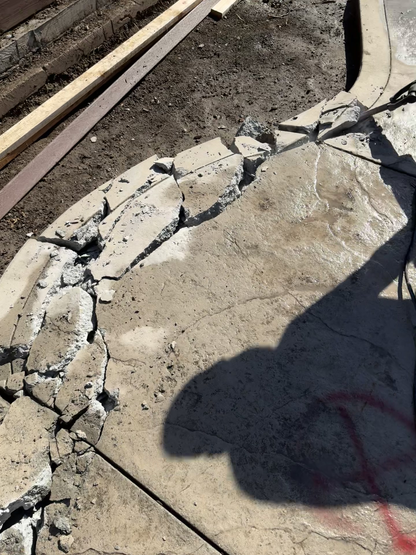 Curved stamped concrete edge broken into several fractured pieces during a Quartz demolition project