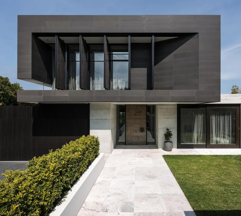 Modern dark-toned two-story house exterior with a landscaped entry walkway